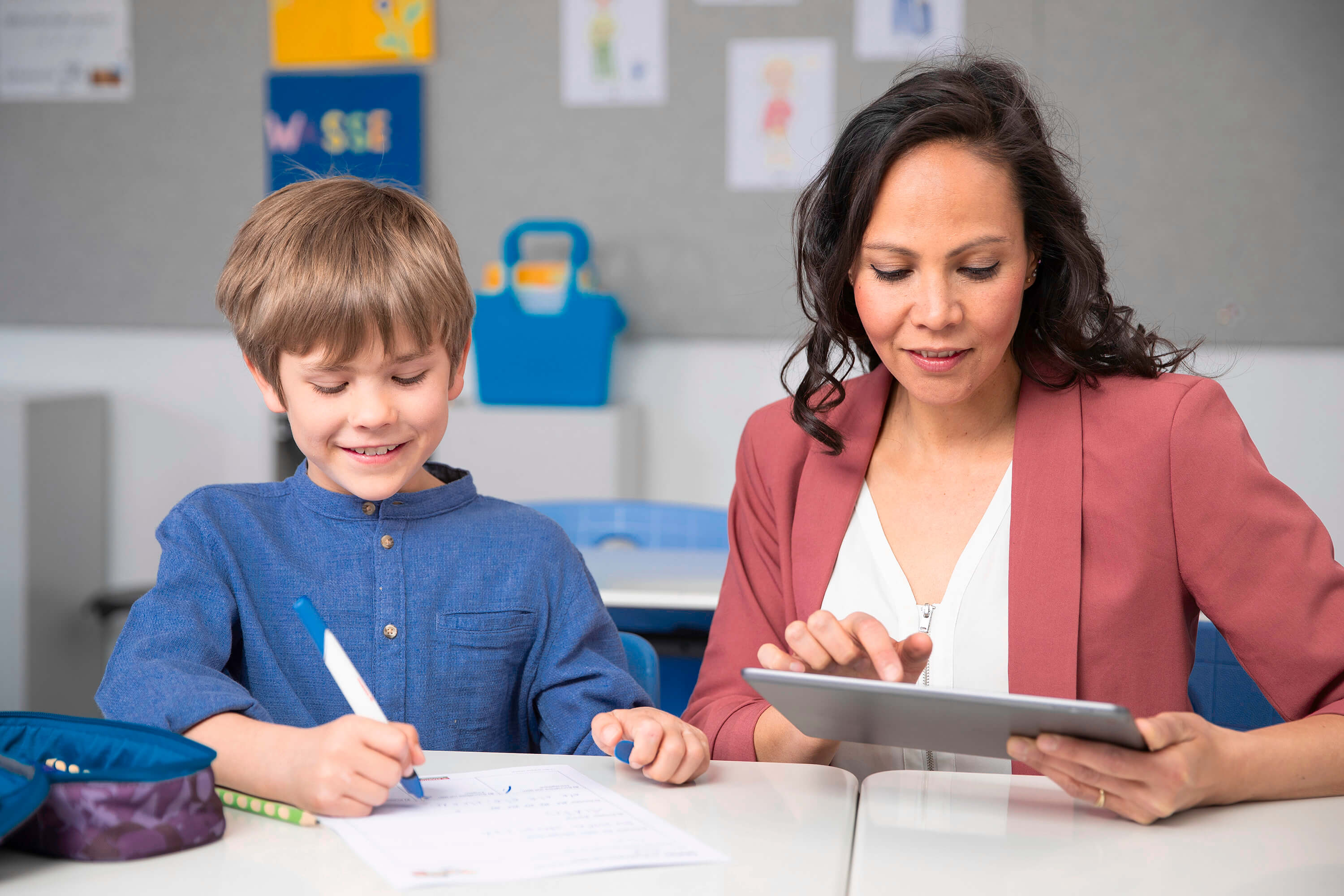 Lehrerin hilft einem Schüler beim Arbeiten mit einem Tablet und dem STABILO EduPen Neo.