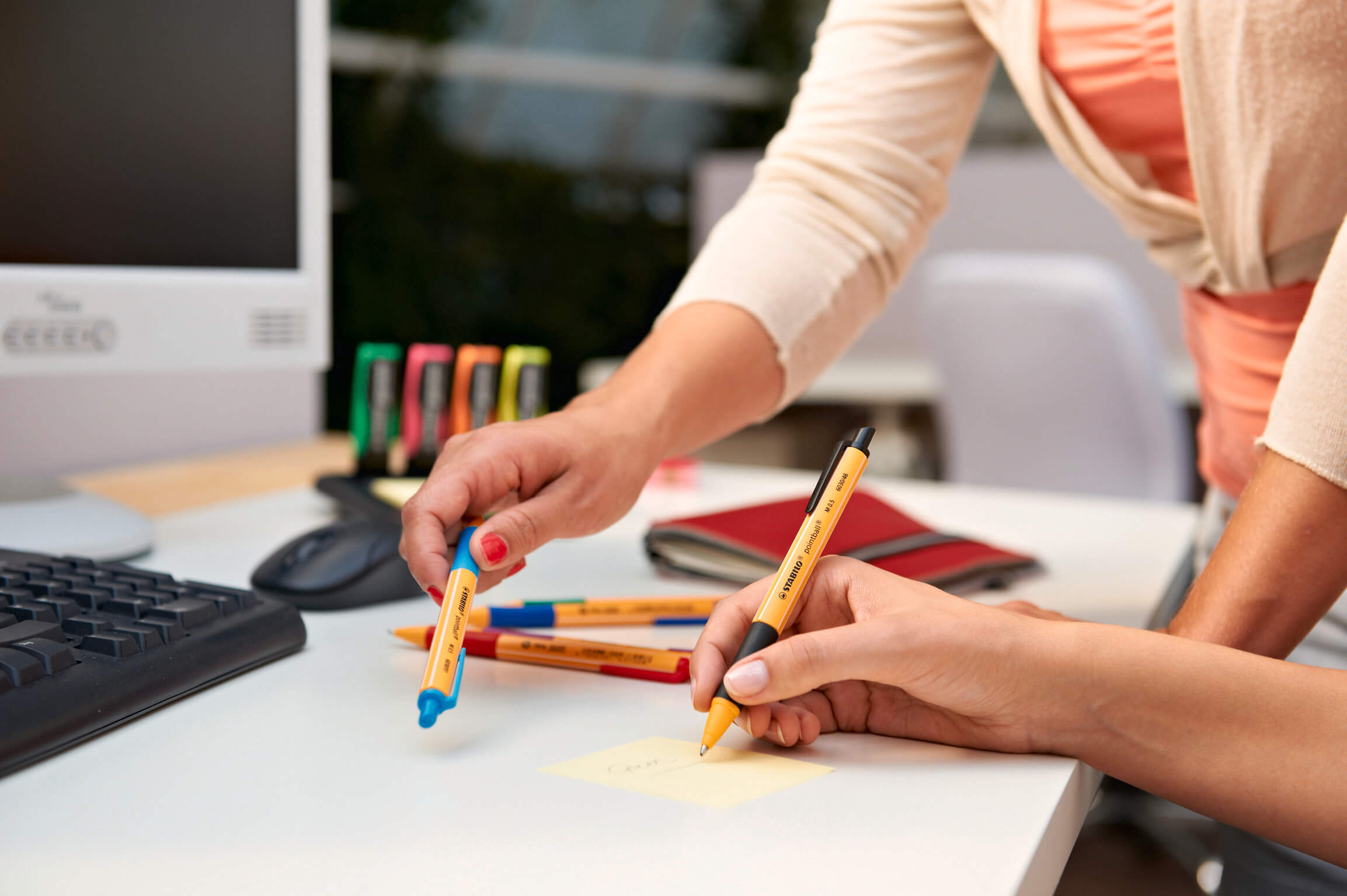 Hände mit STABILO-Stiften, die Notizen auf einem Tisch machen